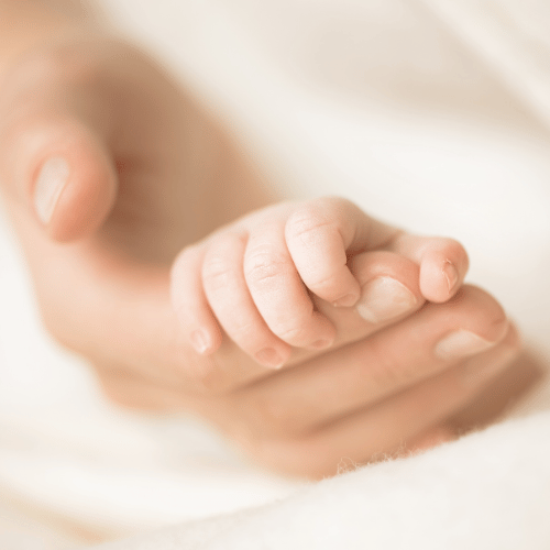 a baby holding its mothers finger as a result of fertility reflexology